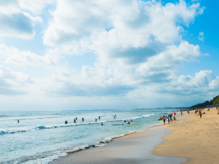 Seminyak beach bustling with swimmers and surfers.
