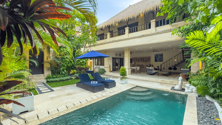 Luxurious tropical villa with a private pool, lush greenery, sun loungers, and open-air living space at Villa Bugis in Seminyak, Bali.