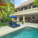 Luxurious tropical villa with a private pool, lush greenery, sun loungers, and open-air living space at Villa Bugis in Seminyak, Bali.