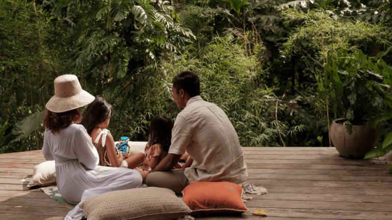 A family relaxing together on a wooden deck surrounded by lush tropical greenery, showcasing serene and bonding moments perfect for family activities in Bali.
